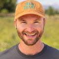 Front view of man wearing light brown Carhartt canvas baseball cap with embroided orange and teal logo that reads: TRAIN SMART Everytown Firearms Training.