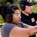 Side view of woman wearing clear Carhartt Billings safety glasses with a small orange Train SMART logo on the side. 