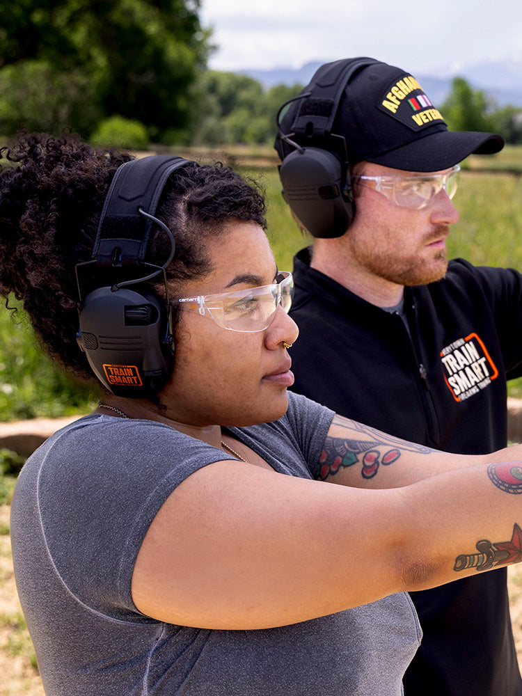 Side view of woman wearing clear Carhartt Billings safety glasses with a small orange Train SMART logo on the side. 