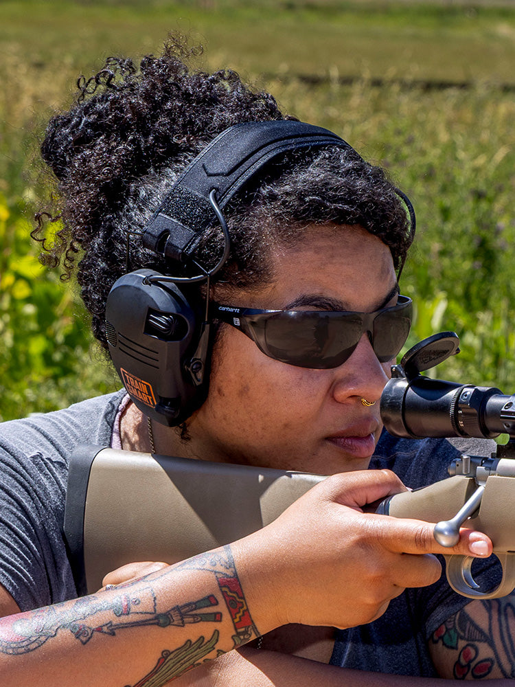 Woman wearing gray-tinted Carhartt Billings safety glasses with a small white Train SMART logo on each side.