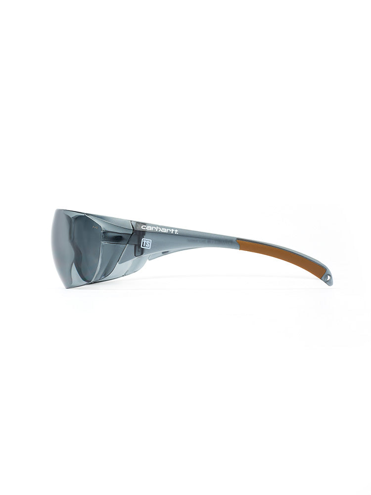 Side view of gray-tinted Carhartt Billings safety glasses with a small white Train SMART logo on each side.