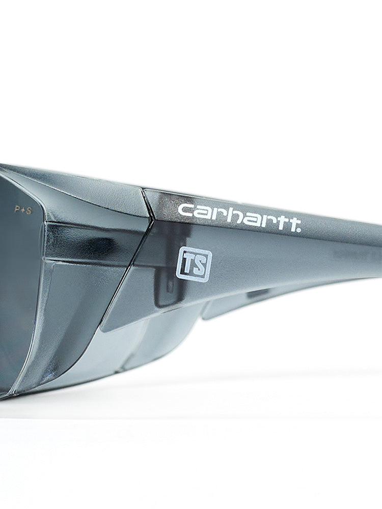 Close-up side view of gray-tinted Carhartt Billings safety glasses with a small white Train SMART logo on each side.